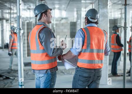 Vue arrière du chef de site et le constructeur rencontre avec blueprint on construction site Banque D'Images