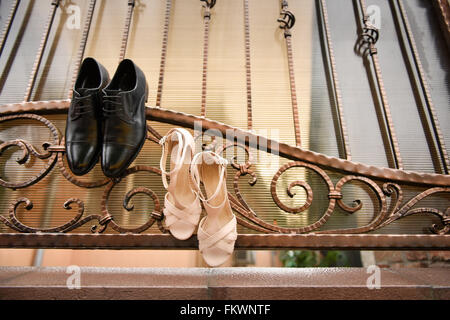 Groom chaussures noires et blanches chaussures suspendu dans une clôture en fer forgé Banque D'Images