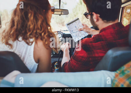 Vue arrière d'un jeune couple dans leur voiture de la vérification d'une carte. Jeune homme et femme sur un road trip. Banque D'Images