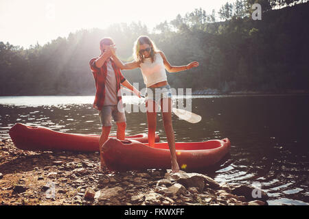 Jeune homme femme aidant à sortir du canot. Couple après la balade en canoë dans le lac. Banque D'Images