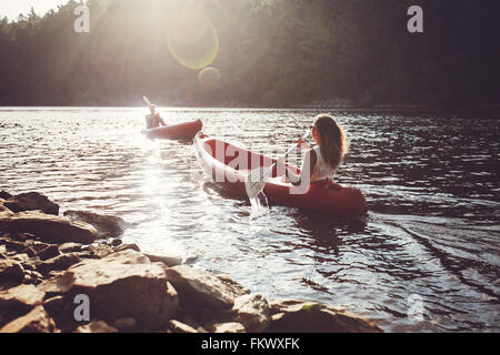 Les jeunes kayak dans un lac. Young man and woman paddling kayak sur une journée ensoleillée. Banque D'Images