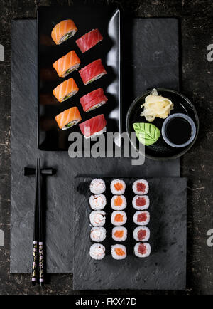 Set à Sushi nigiri et rouleaux servi avec des baguettes et de la sauce soja sur ardoise noire. Mise à plat. Banque D'Images