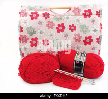 Tricot à motifs fleurs rose / artisanat sac avec des aiguilles à tricoter, tricot et deux boules rouges de la laine. Banque D'Images