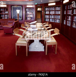 Bibliothèque classique avec des fauteuils en cuir, table en pierre et atlas du monde sur la table. Banque D'Images