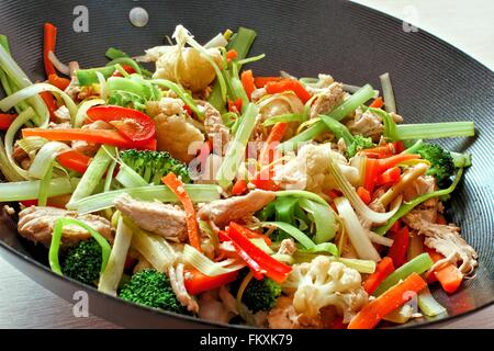 Faire sauter les légumes mélangés avec du poulet dans un wok close up Banque D'Images