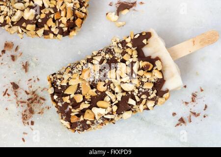 Sucettes glacées au chocolat fait maison avec des écrous. Vue aérienne contre un arrière-plan en marbre blanc. Banque D'Images