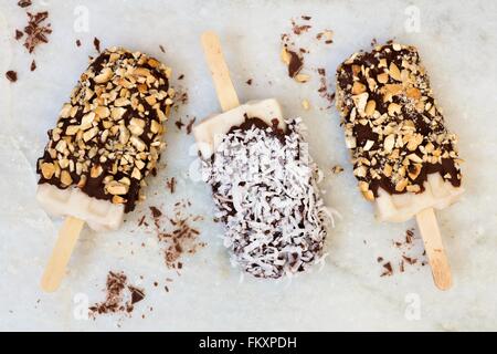 Des sucettes au chocolat et noix de coco. Vue aérienne contre un arrière-plan en marbre blanc. Banque D'Images