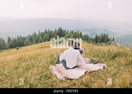 Couple sitting in plaid sur le sommet de la montagne Banque D'Images