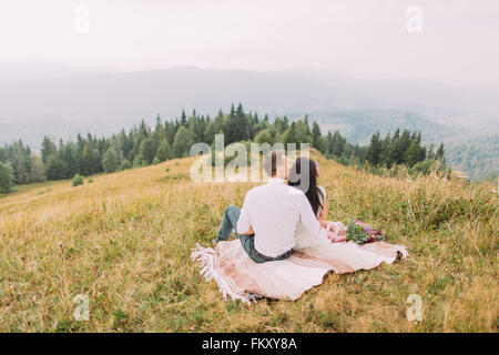 Couple assis dans le plaid sur sommet de montagne Banque D'Images