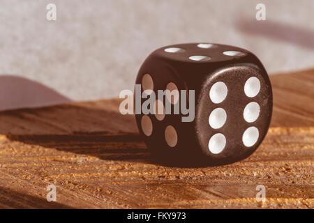 Close-up of a black dice sur une surface en bois, avec fanée et filtre vintage Banque D'Images