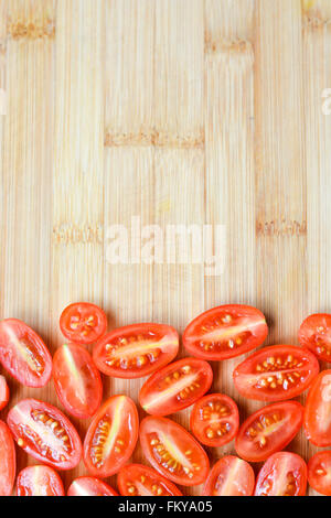 Tomates cerises rouges hachés sur une planche à découper en bois Banque D'Images