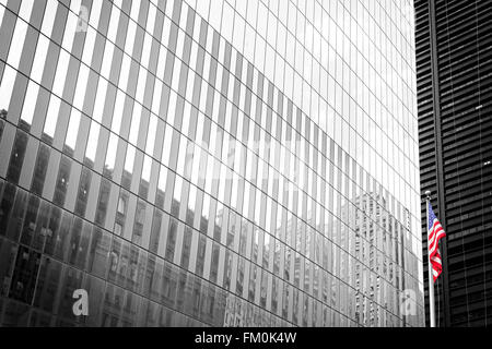 Drapeau américain devant un bâtiment blanc et noir mur de verre, New York, USA. Banque D'Images
