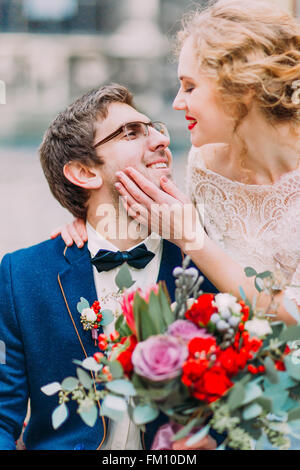 Blonde bride aristocratique touche doucement son visage du marié Banque D'Images