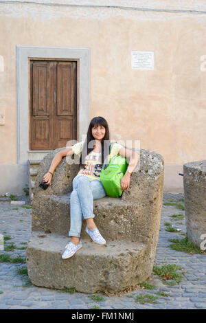 Belle jeune fille assise sur un rocher grand fauteuil dans un antique village appelé Calcata, Italie Banque D'Images