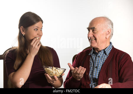 Jeune femme et senior homme mange du popcorn Banque D'Images