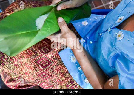 Woman wrapping de riz collant dans la feuille de banane Banque D'Images