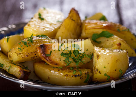 Close up de quartiers de pommes de terre au four avec du persil sur la plaque Banque D'Images