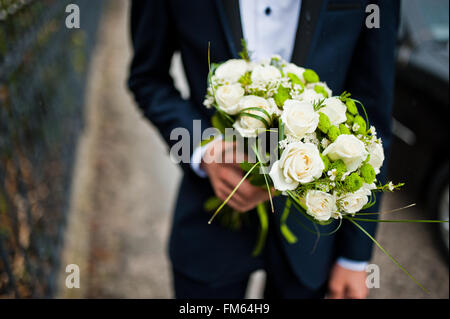 Groomsman tenir en main deux bouquets de demoiselles d'honneur Banque D'Images