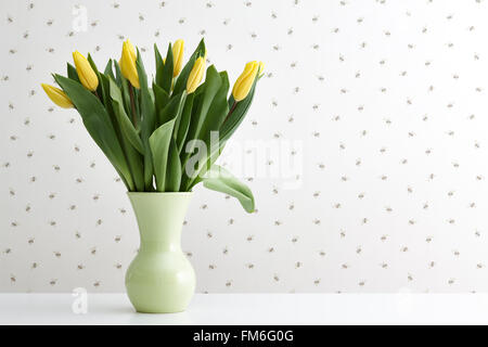 Tulipes jaunes dans un vase vert Banque D'Images