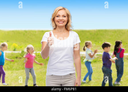 Woman showing Thumbs up sur le groupe des petits enfants Banque D'Images