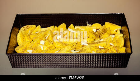 Pommes de terre pelées brut avec des épices et des tranches de beurre prêt à être rôti bac d'alimentation. Banque D'Images