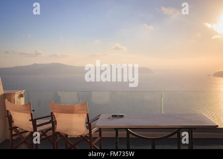 Deux chaises vides sur un balcon à Santorin, face au coucher de soleil sur la Mer Banque D'Images