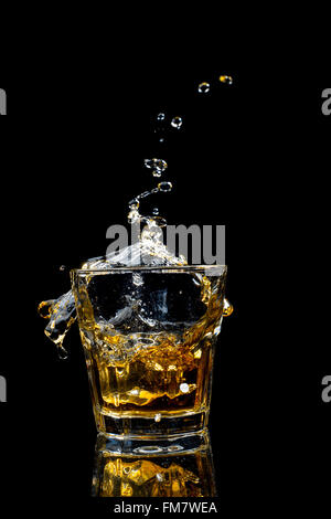 Whiskey splash en verre isolé sur fond noir. Banque D'Images