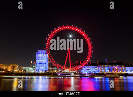 Londres de nuit - grande roue London Eye illuminée et sur les toits de la ville la nuit, la pleine lune qui brille derrière Banque D'Images