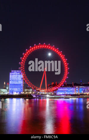 Londres de nuit - grande roue London Eye illuminée et sur les toits de la ville la nuit, la pleine lune qui brille derrière Banque D'Images