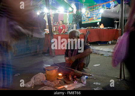 Un homme sans vision (aveugle) joue un instrument de musique traditionnel à une foire de rue dans la région de Kampong Cham, au Cambodge. Banque D'Images