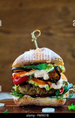 Burger végétarien fait de champignons, pois chiches et brocoli rôti avec du poivre, des aubergines, des feuilles de roquette et de l'avocat en purée Banque D'Images