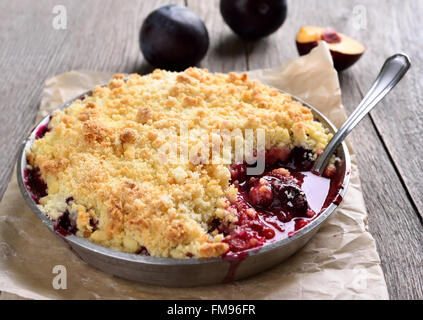 Plum crumb la cuisson dans le moule, sur fond de bois Banque D'Images