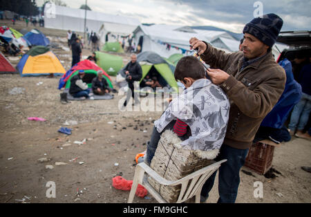 Idomeni, Grèce. Mar 11, 2016. Un enfant réfugié obtenir une coupe dans le camp de réfugiés en Idomeni, Grèce, 11 mars 2016. Depuis la frontière a été fermée, 12 500 réfugiés vivent dans le camp. Photo : Kay Nietfeld/dpa/Alamy Live News Banque D'Images