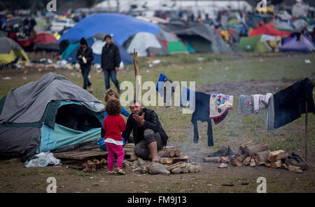 Idomeni, Grèce. Mar 11, 2016. Un homme avec deux enfants assis en face de sa tente dans le camp de réfugiés en Idomeni, Grèce, 11 mars 2016. Depuis la frontière a été fermée, 12 500 réfugiés vivent dans le camp. Photo : Kay Nietfeld/dpa/Alamy Live News Banque D'Images