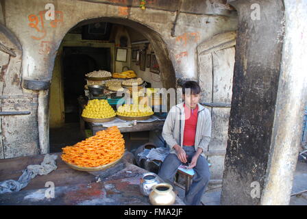 Jeune Indien assis en étal de bonbons Banque D'Images