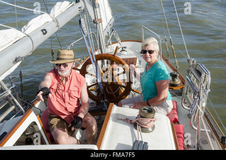 Un couple de personnes âgées sur leur voilier ketch classique comme il le fait d'indications de vent sur l'eau de l'avant alors qu'elle les plans tremblotants la barre. Banque D'Images