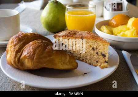 Petit déjeuner à l'hôtel avec gâteau, fruits et jus d'orange Banque D'Images