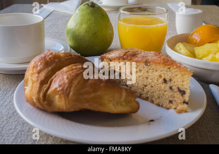 Petit déjeuner à l'hôtel avec gâteau, fruits et jus d'orange Banque D'Images