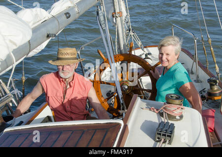 Une happy senior couple jouit d'temps ensemble de la voile sur un lac sur une belle journée d'été. Banque D'Images