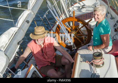 Une happy senior couple jouit d'temps ensemble de la voile sur un lac sur une belle journée d'été. Banque D'Images