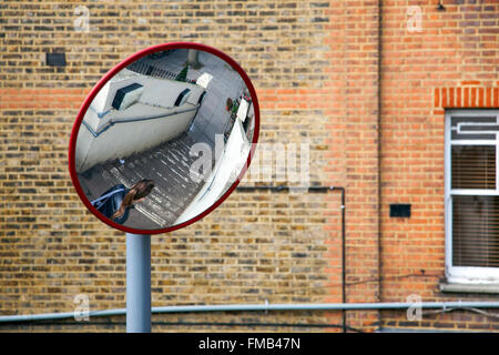 Miroir convexe de sécurité une réflexion femme marche dans les escaliers dans un espace public avec une faible visibilité Banque D'Images