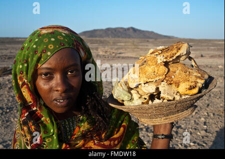 Jeune femme appartenant à la tribu des Afar. Elle tient un panier plein de 'mufé" ( pain). ( Ethiopie) Banque D'Images