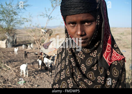 Jeune femme musulmane appartenant à la tribu des Afar. Derrière elle, le camp d'où elle vit est visible (Éthiopie) Banque D'Images