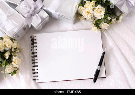 Album de mariage ou de l'écriture de livre sur la dentelle mariée avec plusieurs cadeaux de mariage d'argent et rose blanche bouquets. L'espace pour copier. Banque D'Images