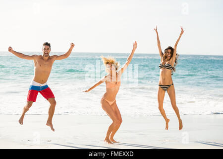 Belle amis excités de sauter sur la plage Banque D'Images