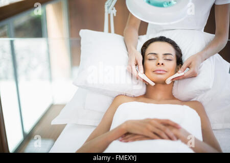 Jeune femme avec les yeux fermés tout en recevant un massage du visage Banque D'Images