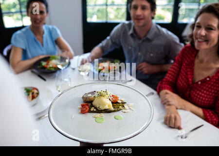 Waiter serving meal pour groupe d'amis Banque D'Images