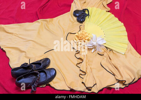 Vêtements jaune pour danse flamenco. Chaussures noires, le papier rose et des castagnettes sont posé sur une sous-couche rouge. Banque D'Images