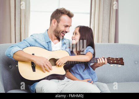 Homme jouant de la guitare avec sa fille à la maison Banque D'Images