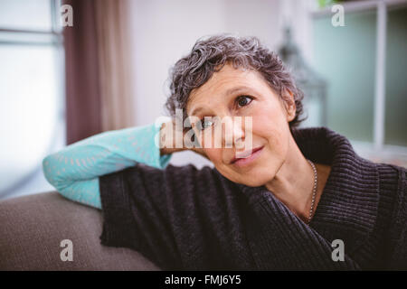 Thoughtful mature woman sitting on sofa Banque D'Images